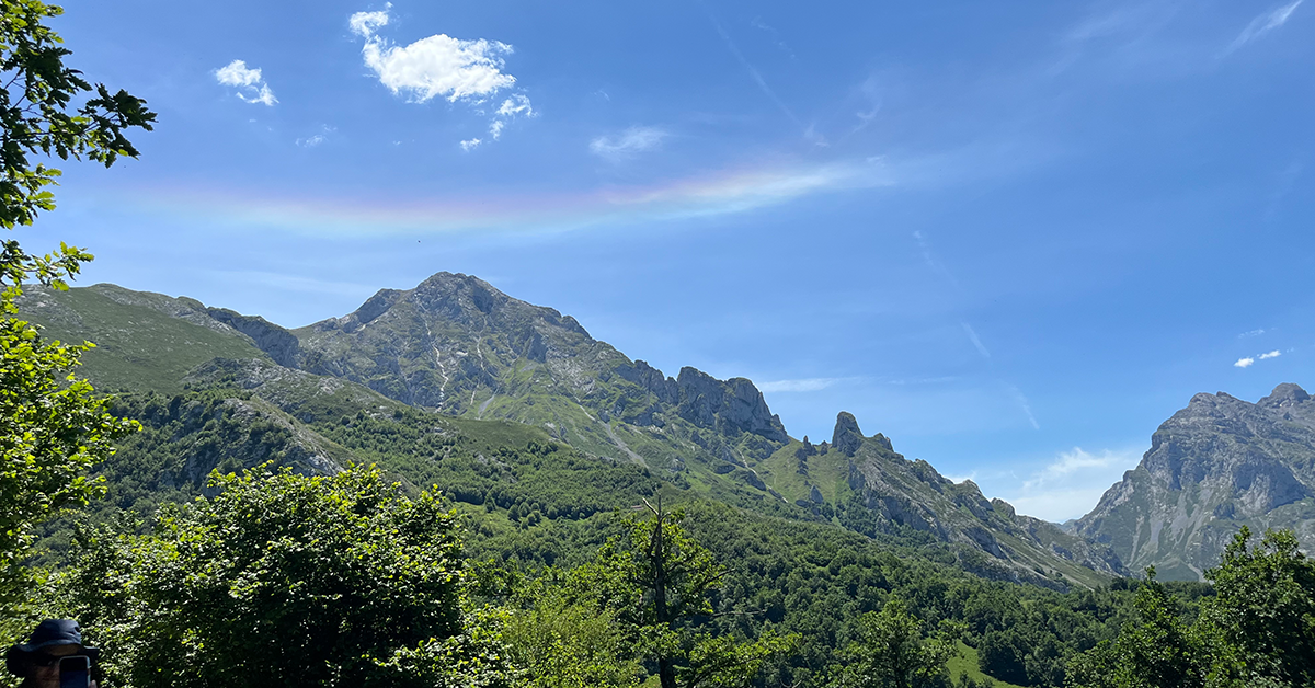A mountain with a clear sky and a stripe of rainbow above