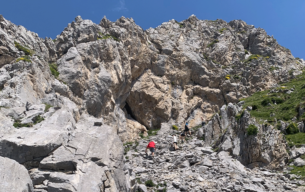 Hikers scrambling up a rocky peak