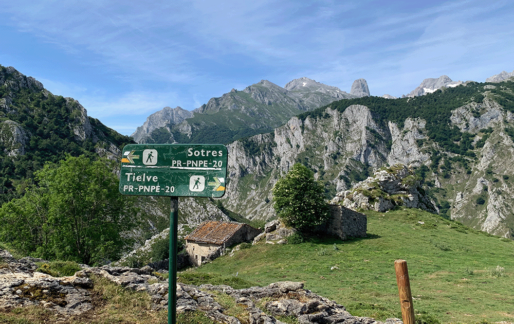 Trail sign for Sotres and Tielve in front of mountains